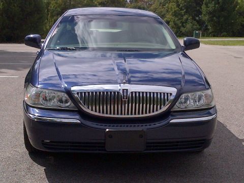 2001 Ford Crown Victoria - Front view of a dark blue Lincoln Town Car with a prominent chrome grille and emblem.