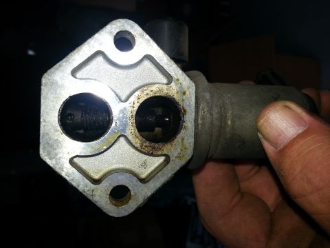 1994 Ford Bronco - A close-up view of a throttle body, a critical engine component, held by a person's hand.