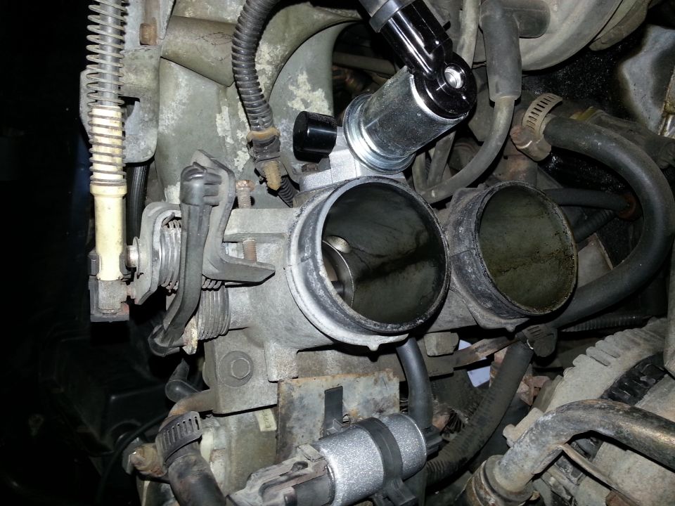 Close-up of a vehicle's throttle body assembly with hoses and wiring