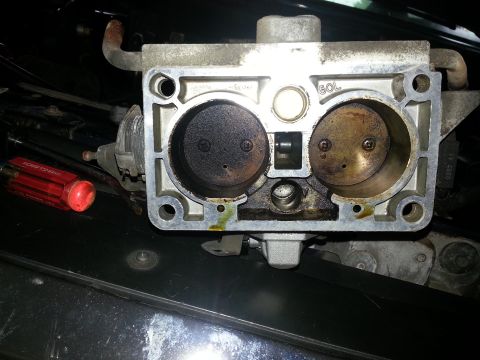 1994 Ford Bronco - Close-up of a dirty throttle body, showing internal components and some fluid leakage.