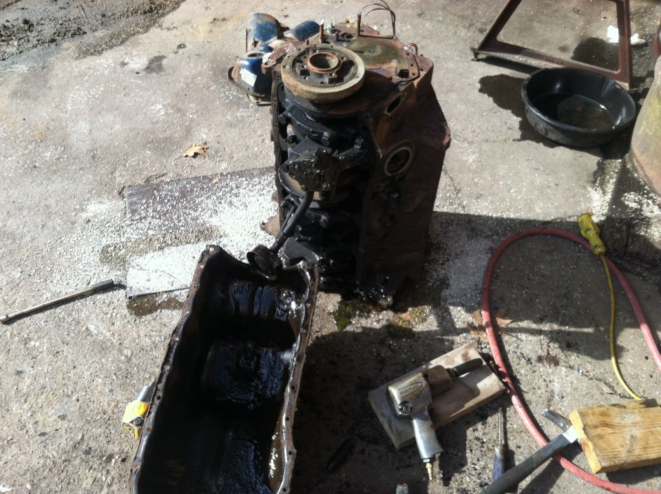 Engine block and detached oil pan on concrete with tools