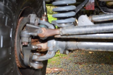1989 Ford Bronco - Detail shot of the front suspension and tire of an unidentified vehicle, showing wear and rust.