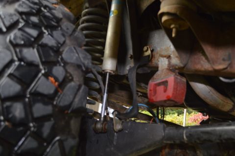 1989 Ford Bronco - The underside of a vehicle shows a large tire, suspension components, and rusty metal parts.