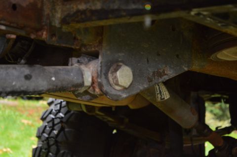1989 Ford Bronco - Close-up of vehicle undercarriage components, including suspension and a tire. Some text is visible on a shock absorber.