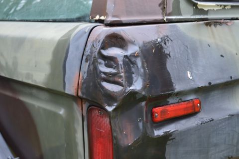 1989 Ford Bronco - The rear quarter panel of a vehicle shows significant damage and a broken taillight assembly.