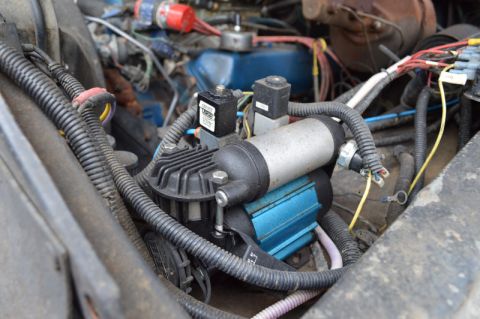 1989 Ford Bronco - Close-up view of an aftermarket air compressor installed in the engine compartment of a vehicle.