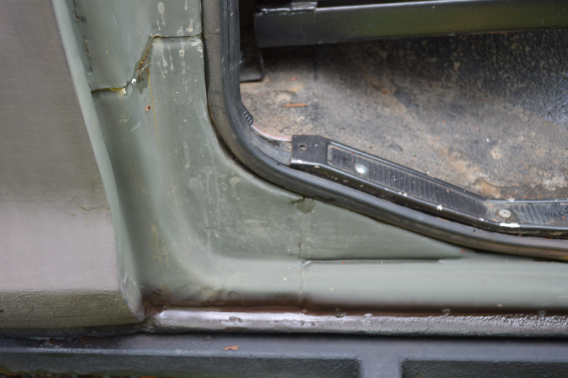 Close-up of vehicle door jamb and interior floor showing wear and some rust