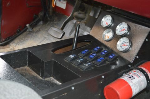 1989 Ford Bronco - The vehicle's interior features a custom console with auxiliary switches and gauges, alongside a mounted fire extinguisher.
