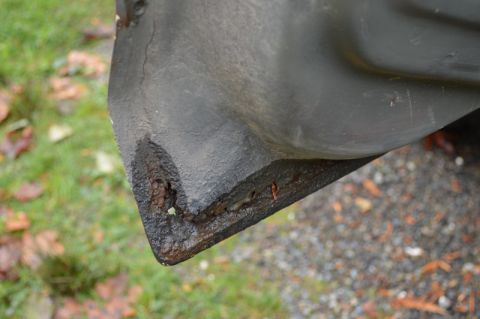 1989 Ford Bronco - The lower corner of a vehicle shows significant rust and damage, indicating wear and tear.
