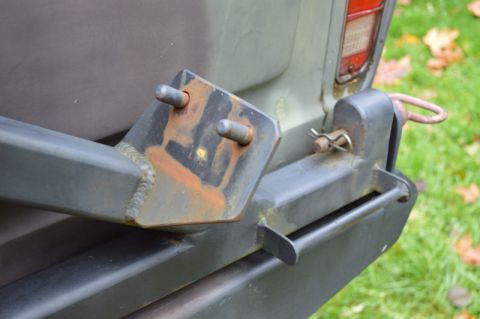 1989 Ford Bronco - A close-up view of a vehicle's rear bumper and tow hitch mount, with visible rust and hardware.