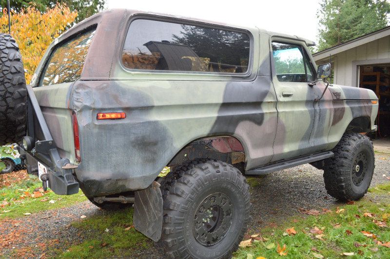 Camouflaged Ford Bronco with large tires and spare tire on the rear