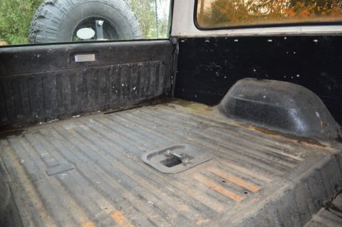 1989 Ford Bronco - The cargo area of a 1989 Ford Bronco shows its utilitarian design, with a spare tire visible through the rear window.
