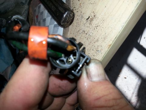 1994 Ford Bronco - Hand holding a damaged electrical connector with exposed wires and orange tape.