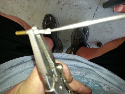 1994 Ford Bronco - A person uses pliers to adjust a component connected to a white cable.