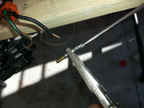 1994 Ford Bronco - Close-up of a wiring harness connector and a tool crimping a wire terminal.