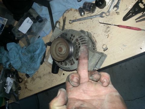 1994 Ford Bronco - Photograph of an alternator held over a workbench, not a technical document.