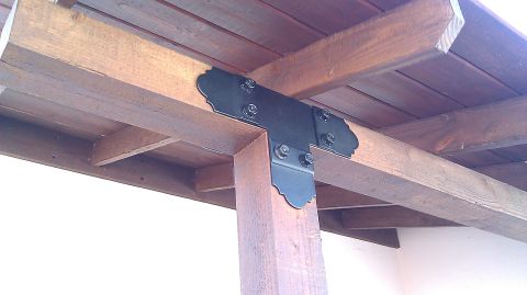 1996 Ford Bronco - A decorative black metal bracket secures wooden beams and a support post on an outdoor structure.