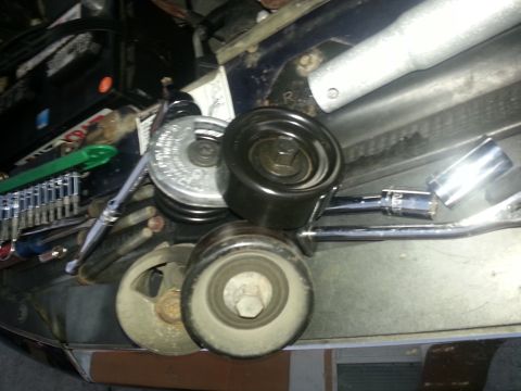 1994 Ford Bronco - Alternator pulley and tensioner assembly with tools laid out.