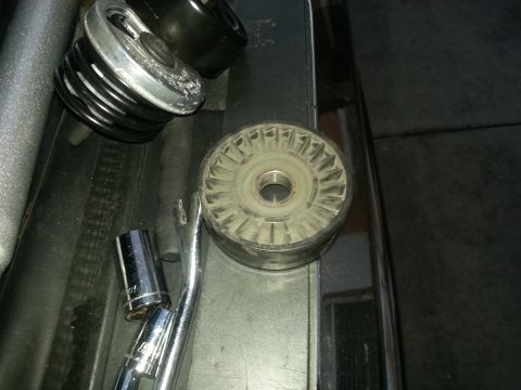 1994 Ford Bronco - Close-up of automotive parts, including an alternator pulley and a fan clutch, with tools nearby.