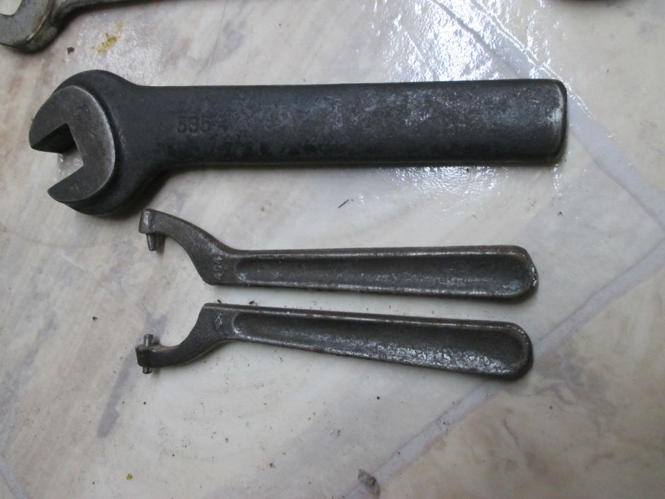 Three metal wrenches on a tiled surface. One large wrench has '535' stamped on it