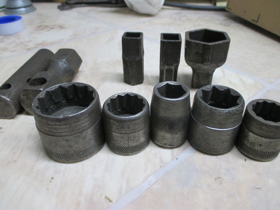 Set of socket wrenches and extensions on a tiled surface. One socket has '16' marked on it