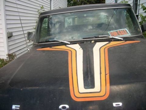 1978 Ford Bronco - A black Ford truck with a distinctive racing stripe graphic on its hood is parked outside a home.