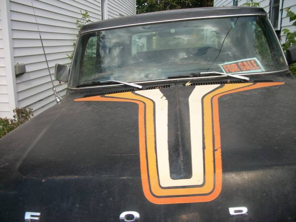 Black Ford truck hood with orange and white racing stripes, cracked windshield with a 'FOR SALE' sign