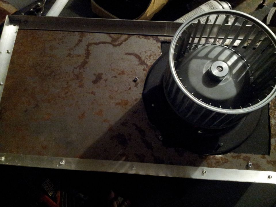 Blower motor assembly on a rusty metal panel with visible water stains