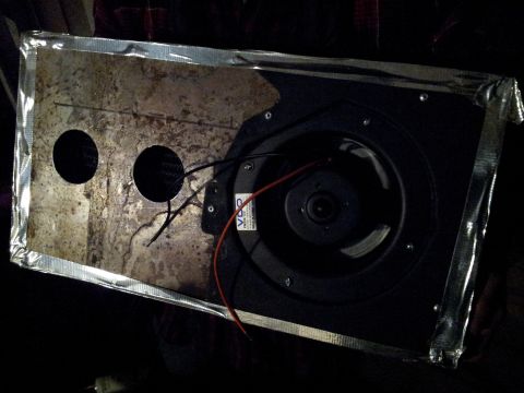 1973 Ford Ranchero - A speaker assembly with two circular openings and exposed wires, its edges reinforced with tape.