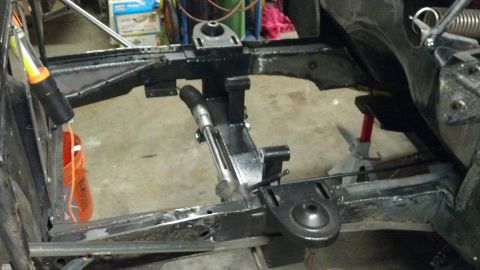 1964 Ford Fairlane - Close-up view of a car's frame and suspension system, showing various metal components and a jack stand supporting the structure.