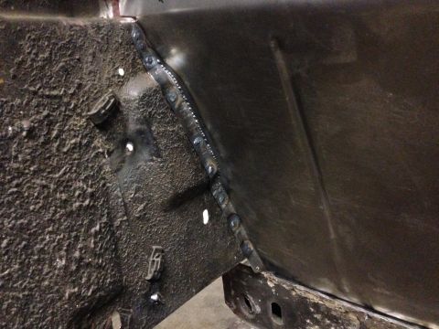 1964 Ford Fairlane - Close-up of a freshly welded metal panel on a vehicle's frame, showing repair work.