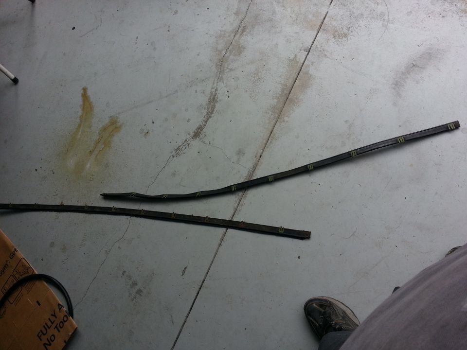 Two black rubber trim pieces with yellow clips on concrete floor