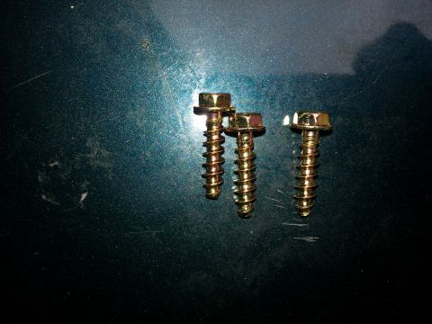 1994 Ford Bronco - Three gold screws are shown against a dark green, scratched surface with a visible watermark.