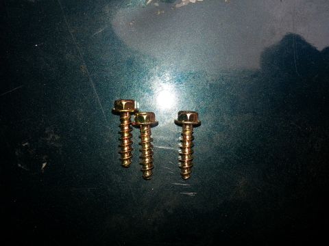 1994 Ford Bronco - Three gold screws are shown on a dark green surface, with the Supermotors.net logo in the lower right corner.