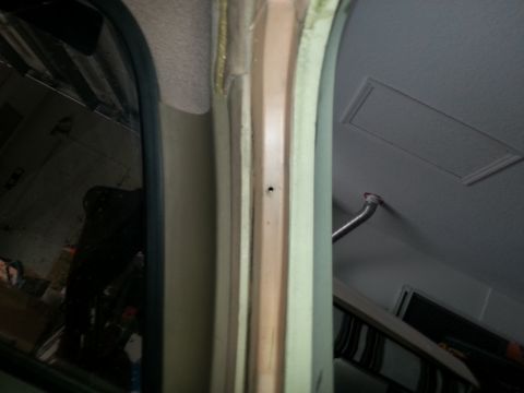 1994 Ford Bronco - The interior of a vehicle shows a door frame and ceiling, with a small hole in the frame.