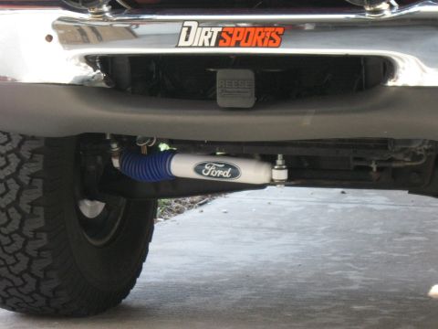 1999 Ford Ranger - Close-up of a Ford shock absorber mounted beneath the front bumper, which has a "Dirt Sports" decal.