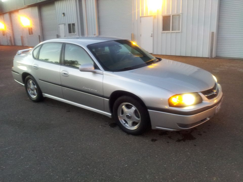 Silver sedan parked outside a warehouse. The 'Impala' badge is visible on the side