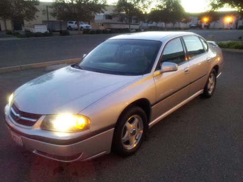 2001 Chevrolet Impala - Silver sedan parked on asphalt with headlights on, viewed from the front left quarter.