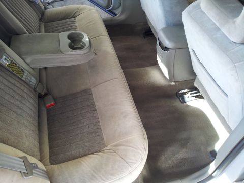 2001 Chevrolet Impala - The rear interior of a car, cloth seats and a center armrest with cup holders.