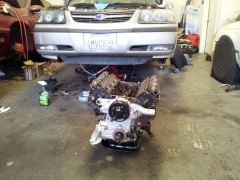 2001 Chevrolet Impala - A silver Chevrolet Impala has its engine removed and placed on the floor in a garage.