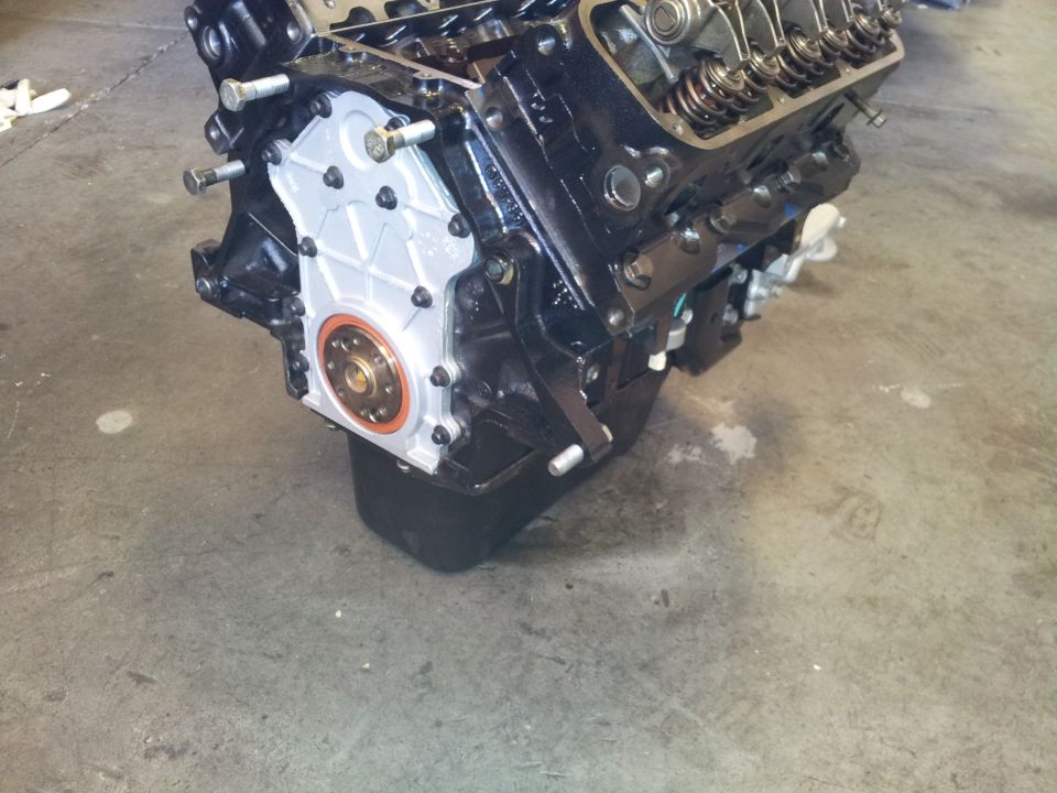 Rebuilt V8 engine long block on shop floor with timing cover and crank seal