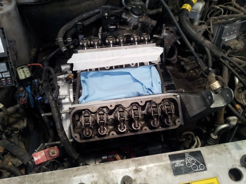 Engine with valve covers removed, showing rocker arms and a blue cloth covering the cylinders