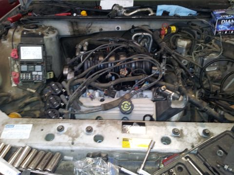 2001 Chevrolet Impala - A view of a car's engine compartment, showing various components and tools ready for work.