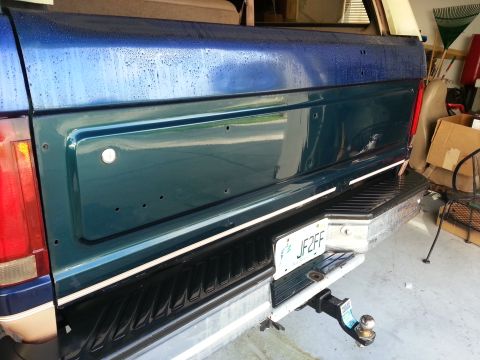 1994 Ford Bronco - The tailgate of a Ford F-Series truck is visible, with a license plate and trailer hitch attached.