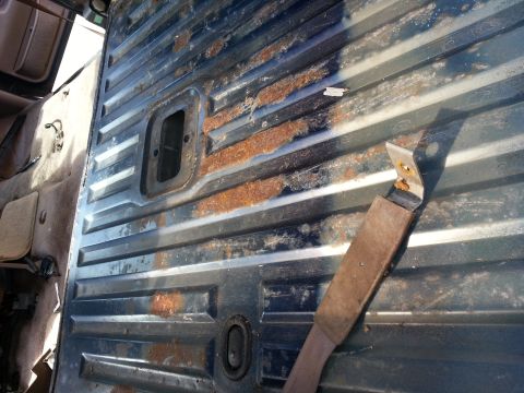 1994 Ford Bronco - Interior view of a vehicle's floor showing significant rust and a damaged seatbelt.