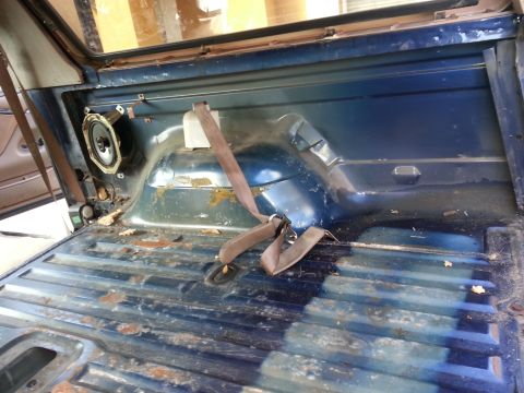 1994 Ford Bronco - The interior cargo area of a vehicle shows a speaker and a seatbelt, with visible wear and tear.