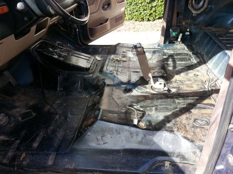 1994 Ford Bronco - The interior floor of a vehicle is visible, stripped of its seats and carpeting, showing the bare metal structure.