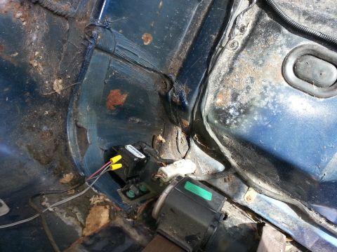 1994 Ford Bronco - The interior of a vehicle shows significant rust and exposed wiring in the rear wheel well area.