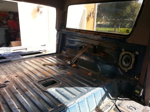 1994 Ford Bronco - The interior of a vehicle is shown with a rusted floor and exposed speaker.