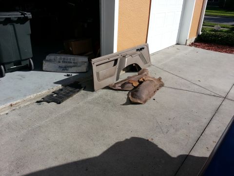 1994 Ford Bronco - Interior door panel and carpet pieces are laid out on a concrete driveway.